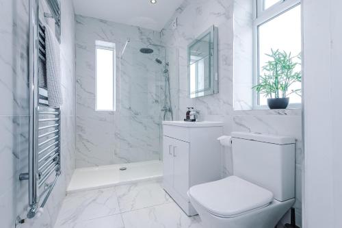 a white bathroom with a toilet and a shower at "Eastville Court Rhyl" by Greenstay Serviced Accommodation - Cosy 2 Bedroom Bungalow with Parking, Netflix & Wi-Fi, Close To Beaches, Shops & Restaurants - Ideal for Families, Business Travellers & Contractors in Rhyl