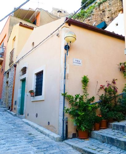 a building on a street with potted plants at Casetta Santa Venera in Modica