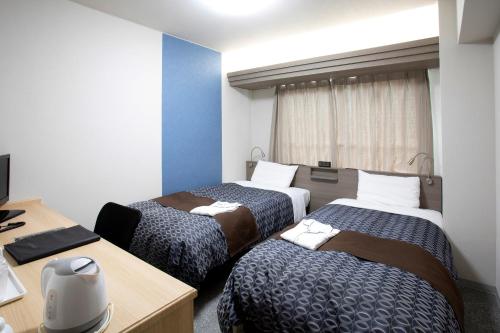 a hotel room with three beds and a desk at Nagasaki IK Hotel in Nagasaki