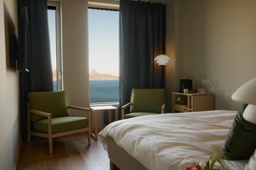 Habitación de hotel con 2 sillas, 1 cama y una ventana en Wood Hotel Bodø, en Bodø