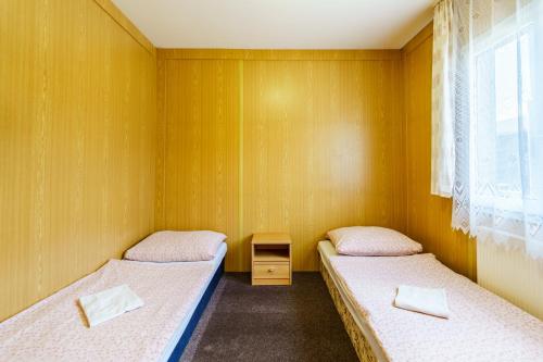 Habitación con 2 camas individuales y paredes de madera. en BeachCamp Nová Role, en Nová Role