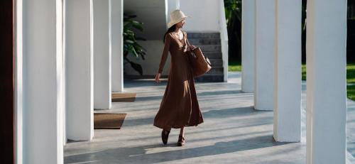 a woman in a dress and hat walking down a hallway at Sanhe Daoli Resort in Qingyuan