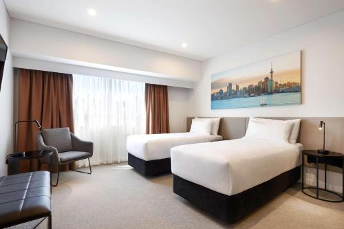a hotel room with two beds and a chair at Travelodge Hotel Auckland Wynyard Quarter in Auckland