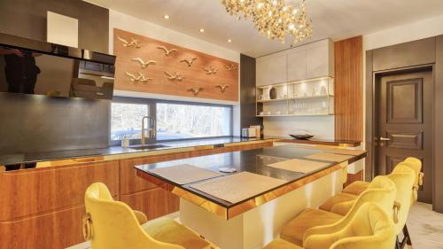 a kitchen with a large island with yellow chairs at Imperia Luxury Residence in Braşov