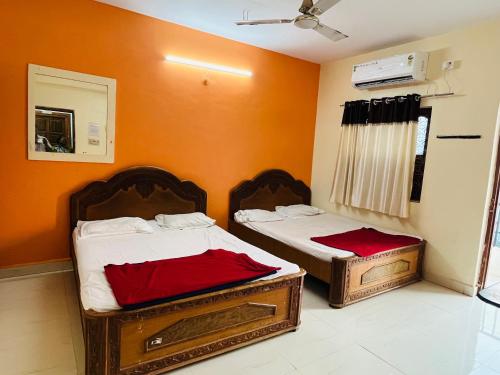 two beds in a room with orange walls at Hotel Raghunath Residency Niwas in Shirdi