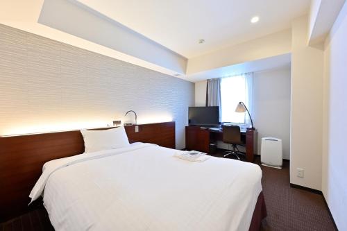 札幌市にあるホテル京阪札幌の白いベッドとデスクが備わるホテルルームです。