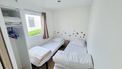 une petite chambre avec deux lits et une fenêtre dans l'établissement Ti Colibri Sables-dOlonne Nord Camping La Plage, à Saint-Hilaire-de-Riez