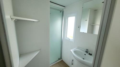 une salle de bain blanche avec un lavabo et un miroir dans l'établissement Ti Colibri Sables-dOlonne Nord Camping La Plage, à Saint-Hilaire-de-Riez