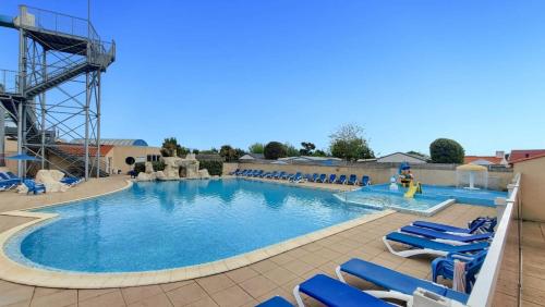 - une grande piscine avec des chaises longues bleues dans un complexe dans l'établissement Ti Colibri Sables-dOlonne Nord Camping La Plage, à Saint-Hilaire-de-Riez