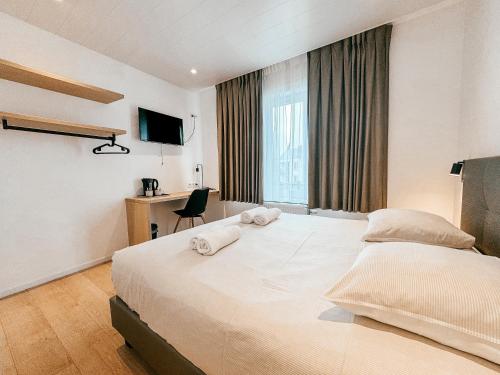 een hotelkamer met een groot bed met handdoeken erop bij Alpha Hotel in Oostende