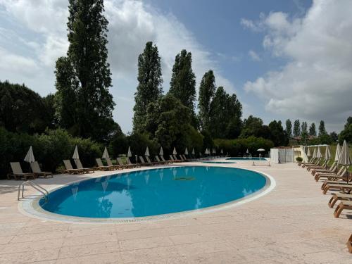 a large swimming pool with lounge chairs and trees at TOCAI Golf & Family Retreat Lignano in Lignano Sabbiadoro