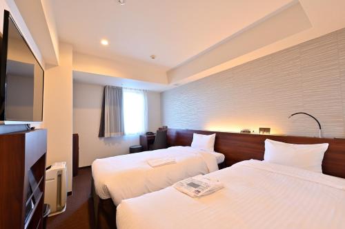 札幌市にあるホテル京阪札幌のベッド2台、薄型テレビが備わるホテルルームです。
