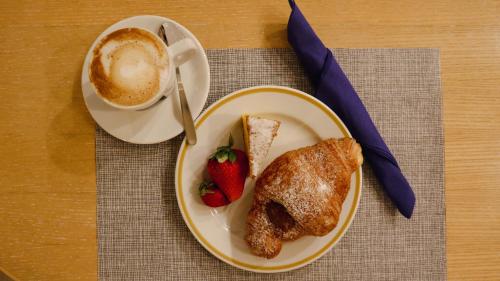 a plate of food with a strawberry and a cup of coffee at Hotel Enzo in Porto Recanati
