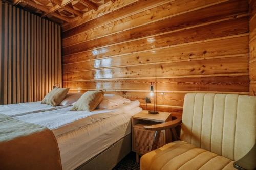 a bedroom with wooden walls and a bed and a chair at Dom Wypoczynkowy U Staszla in Bańska