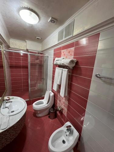 a red and white bathroom with a toilet and a sink at Sary Arka Hotel in Shymkent