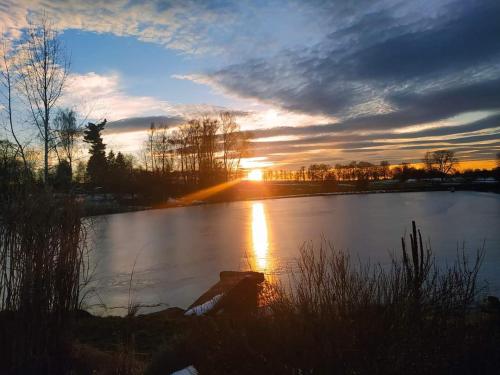 a sunset over a lake with the sun setting at Chalupa u Pramenů in Počátky