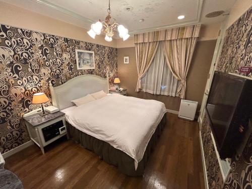 a bedroom with a large bed and a chandelier at HOTEL D-CUBE 明石店 in Higashi-futami