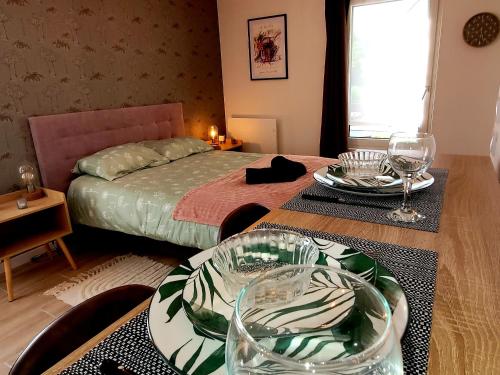 une chambre avec un lit et deux tables avec des verres dans l'établissement L' Écrin de Jade, à Melun