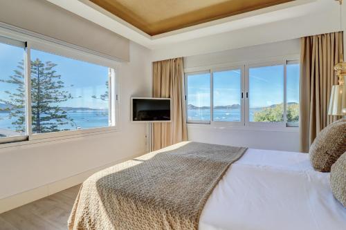 a bedroom with a bed and a tv and windows at Hotel Illa d'Or & Club Apts 4* Sup in Port de Pollensa