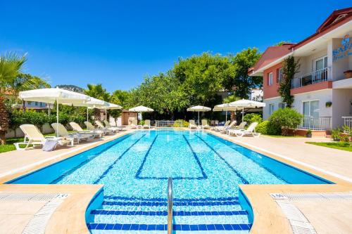 a swimming pool with chairs and umbrellas next to a building at Safak Oasis Hotel in Dalyan