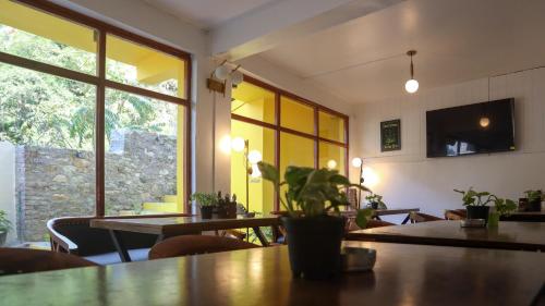 a dining room with tables and chairs and windows at Whoopers Hostel Jibhi in Jibhi