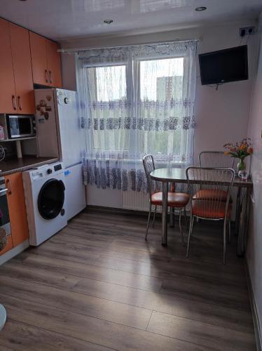 uma cozinha com mesa e cadeiras e uma janela em Apartamentai šalia parko em Siauliai