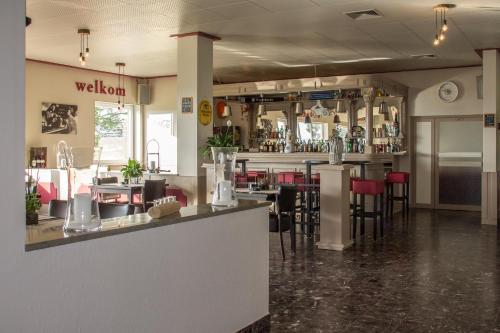 a restaurant with a bar with red chairs at Landhaus Eifelsicht in Hellenthal
