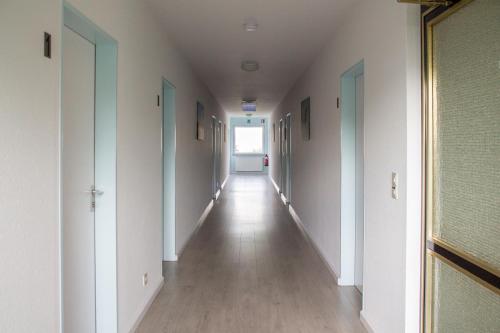 a long hallway with white walls and wooden floors and a window at Landhaus Eifelsicht in Hellenthal