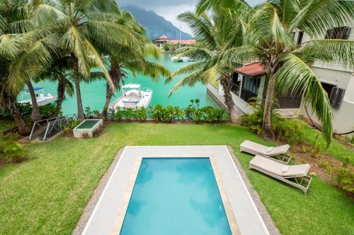an image of a swimming pool on a lawn with palm trees at Maison L'Amirale by Simply-Seychelles in Eden Island