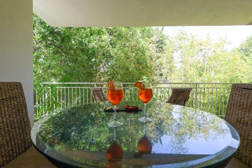 a glass table with two wine glasses on a balcony at B&B Casita GioJa in Gasponi