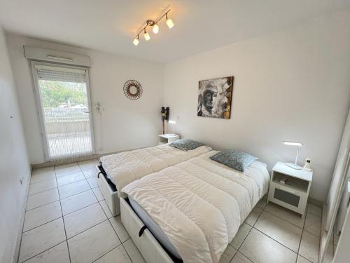 une chambre blanche avec un lit et une fenêtre dans l'établissement Sol-y-Days Indigo, spacieux appartement a deux pas des plages, à La Grande Motte