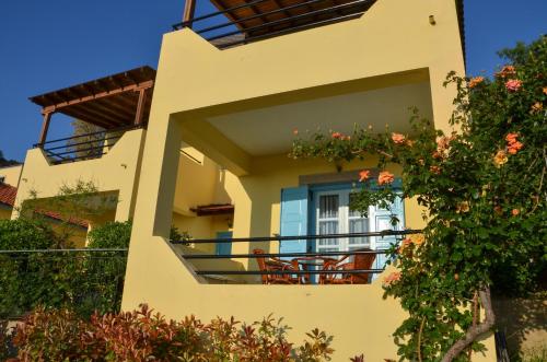 ein gelbes Haus mit einem Balkon mit Blumen in der Unterkunft Hotel Dina - Ξενοδοχείο Ντινα in Plati
