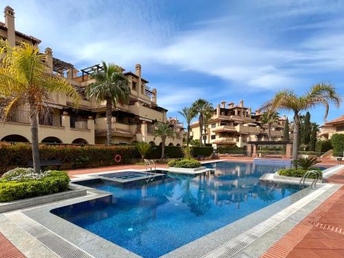 una piscina frente a un edificio con palmeras en Apartamento de Lujo en Resort Isla del Fraile, en Águilas