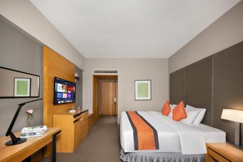 a hotel room with a bed and a flat screen tv at Jianguo Hotel Guangzhou in Guangzhou