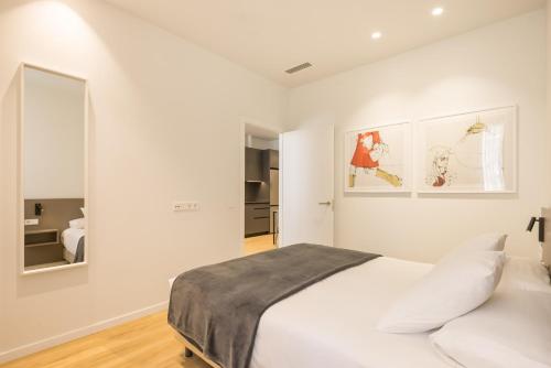 a white bedroom with a bed and a mirror at Mon Suites Jardín de Ayora in Valencia
