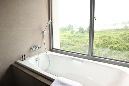 a bathroom with a bath tub and a window at The Botanica Sanctuary in Puncak