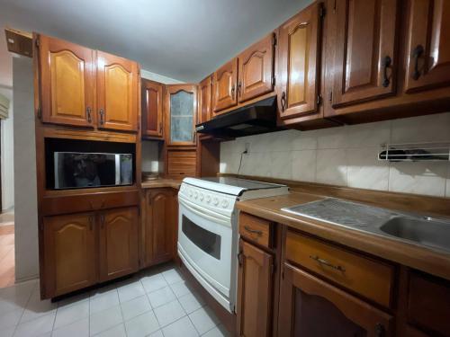 a kitchen with wooden cabinets and a white stove top oven at House Near The Santiago River in San Luis Potosí