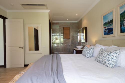 a bedroom with a large white bed with pillows at Maison L'Amirale by Simply-Seychelles in Eden Island