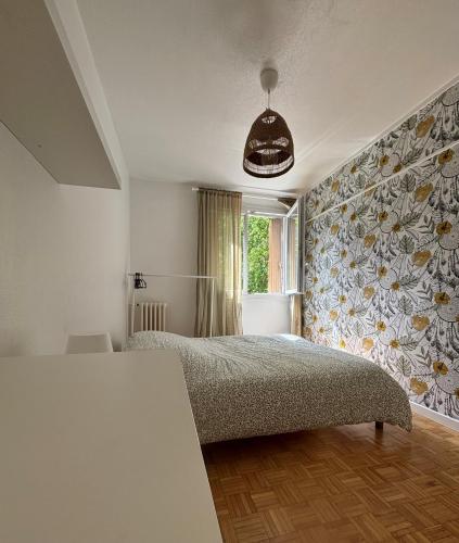- une chambre avec un lit et un mur fleuri dans l'établissement Appartement 3 chambres, à Rennes