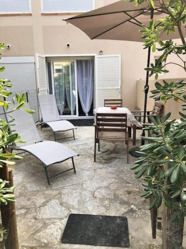 um pátio com uma mesa, cadeiras e um guarda-sol em Appartement d'une chambre a Calvi a 200 m de la plage avec terrasse amenagee em Calvi