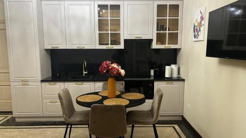 a kitchen with white cabinets and a table and chairs at Mont Blanc Art apartments in Yerevan