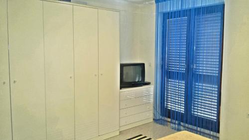 a living room with a tv and a blue curtain at 2 bedrooms apartement at Zlarin 200 m away from the beach with enclosed garden and wifi in Zlarin