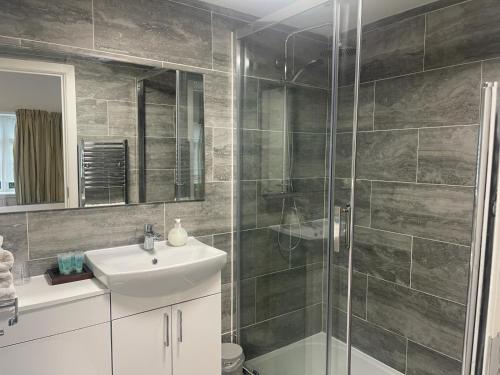 een badkamer met een wastafel en een glazen douche bij The Manor Guest House in Cheadle