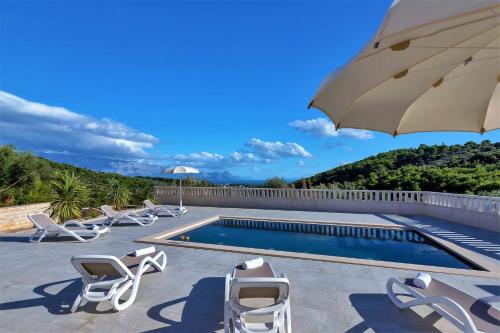 a pool with lounge chairs and an umbrella at Villa Lokanjac in Selca