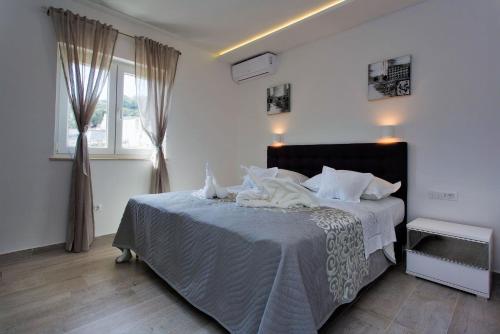 a bedroom with a large bed with white sheets at Villa Lokanjac in Selca