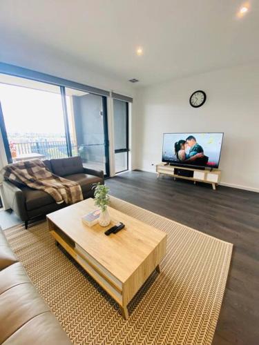 a living room with a couch and a table and a tv at Modern oasis in Rockbank