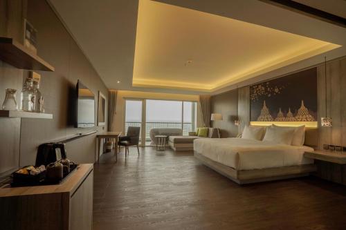 ジョグジャカルタにあるAmaranta Prambanan Yogyakartaのベッドとリビングルームが備わるホテルルームです。