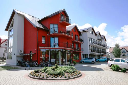 un bâtiment rouge avec un lit fleuri devant lui dans l'établissement Hotel SPA Activia, à Jastrzębia Góra