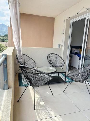 d'un balcon avec trois chaises et une table. dans l'établissement Terrasse de L'Île-Rousse, à LʼÎle-Rousse