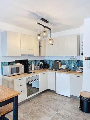 - une cuisine blanche avec des placards blancs et une table dans l'établissement Terrasse de L'Île-Rousse, à LʼÎle-Rousse